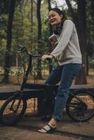 gelukkig Aziatisch jong vrouw wandelen en rijden fiets in park, straat stad haar glimlachen gebruik makend van fiets van vervoer, eco vriendelijk, mensen levensstijl concept. foto