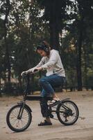 gelukkig Aziatisch jong vrouw wandelen en rijden fiets in park, straat stad haar glimlachen gebruik makend van fiets van vervoer, eco vriendelijk, mensen levensstijl concept. foto