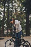 gelukkig Aziatisch jong vrouw wandelen en rijden fiets in park, straat stad haar glimlachen gebruik makend van fiets van vervoer, eco vriendelijk, mensen levensstijl concept. foto