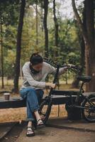 gelukkig Aziatisch jong vrouw wandelen en rijden fiets in park, straat stad haar glimlachen gebruik makend van fiets van vervoer, eco vriendelijk, mensen levensstijl concept. foto