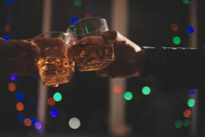 viering nacht, gieten whisky in een glas. geven naar vrienden wie komen naar vieren foto