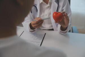 handen van dokter vrouw Holding rood hart, tonen symbool van liefde, menselijk ondersteuning naar geduldig, bevorderen medisch verzekering, vroeg controle voor gezondheidszorg, cardioloog helpen. dichtbij omhoog van voorwerp foto