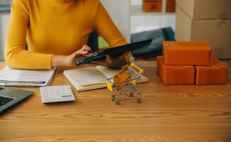 jonge vrouw kleine ondernemer online winkelen thuis. het noteren van bestellingen van klanten met mobiele telefoons. MKB ondernemer of freelance levensstijlconcept. foto