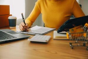 jonge vrouw kleine ondernemer online winkelen thuis. het noteren van bestellingen van klanten met mobiele telefoons. MKB ondernemer of freelance levensstijlconcept. foto