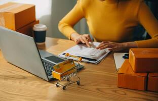 jonge vrouw kleine ondernemer online winkelen thuis. het noteren van bestellingen van klanten met mobiele telefoons. MKB ondernemer of freelance levensstijlconcept. foto