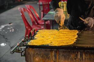 dichtbij omhoog rollen pannenkoek met boter en melk Aan de fornuis in nacht markt van kanchanaburi stad thailand.khanom tokyo of khanom tokiao is een Thais straat tussendoortje foto