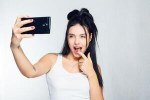 selfie tijd. jong glimlachen blond haar dame aan het doen selfie Aan grijs achtergrond foto