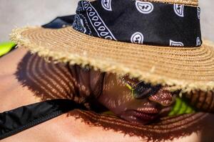vrouw in bikini en rietje hoed aan het liegen Aan tropisch strand foto