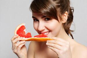 jong mooi vrouw of schattig sexy meisje met lang haar- houdt grapefruit fruit plak foto