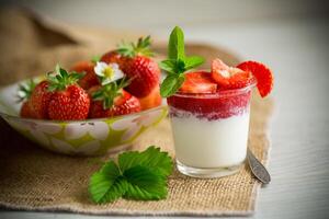 zoet eigengemaakt yoghurt met aardbei jam en vers aardbeien in een glas kop foto