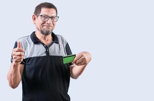 senior Mens met credit kaart maken geld gebaar met vingers, geïsoleerd. senior mensen Holding credit kaart maken geld gebaar, glimlachen Bij camera foto