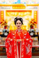 vrouw jurk China nieuw jaar. portret van een vrouw. persoon in traditioneel kostuum. vrouw in traditioneel kostuum. mooi jong vrouw in een helder rood jurk en een kroon van Chinese koningin poseren. foto