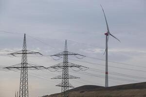 hoog voltage pylonen met wind turbine in Duitse industrieel landschap foto