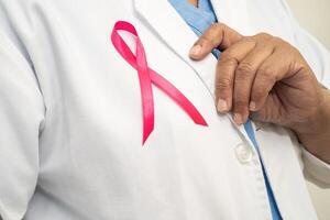 borst kanker, Aziatisch dokter vrouw met roze lint, symbool van wereld borst kanker dag. foto