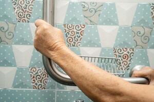 Aziatisch ouderen vrouw gebruik badkamer omgaan met veiligheid in toilet, gezond sterk medisch concept. foto