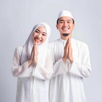 ai gegenereerd hartverwarmend uitbeelding van een jong Aziatisch moslim paar in traditioneel kleding, inclusief hijaab, uitwisselen blij eid mubarak gebaren in een studio instelling met een neutrale kleur palet foto