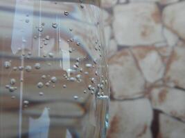 detailopname visie van koolzuurhoudend bubbels in glas met mineraal water Aan steen muur achtergrond foto