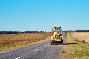 geel trekker Aan platteland weg foto