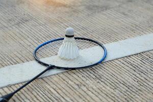 badminton racket en wit shuttle geplaatst Aan groen cement achtergrond. zacht en selectief focus. foto