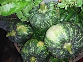 een bundel van groen en zwart squash zittend Aan top van bladeren foto