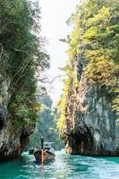 lange staart boten in de mooi zee tussen twee groot rotsen. Thailand. foto