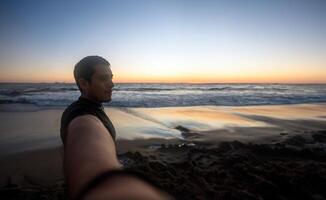 jong Mens nemen een selfie Bij zonsondergang Aan een strand, met ruimte voor tekst foto