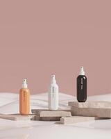 verstuiven flessen van 3 kleuren, geplaatst Aan een beige steen plaat, in een melkachtig, zacht huid zorg concept. verticaal afbeelding. 3d renderen foto