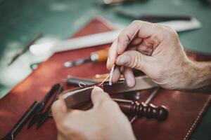 detailopname hand- werken werkwijze leer handgemaakt in de leer werkplaats. Mens Holding bouwen gereedschap en werken. hij is naaien hamer naar maken een portemonnee. bruiner in oud looierij. foto