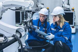 slim ingenieur vrouw team arbeider werken samen onderhoud robot arm in automatisering fabriek industrie foto
