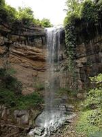 mooi rots muur Bij waterval met planten foto