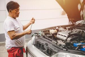 Aziatisch mannetje garage monteur arbeider fix vervangen olie motor onderhoud reparatie gebroken auto foto