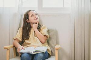 schattig kind meisje lezing een boek en denken nieuw idee. boekenwurm nerdachtig slim kind leren en hebben een vraag foto