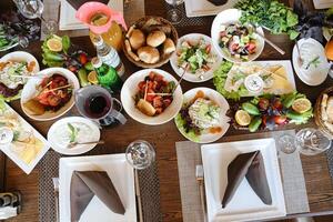 tafel overlopend met schotels van voedsel en bril van wijn foto