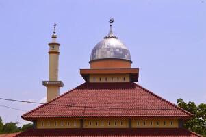 moskee met een schijnend zilver koepel en rood dak, gemarkeerd tegen een Doorzichtig lucht foto
