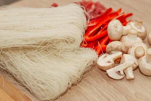gesneden vlees, champignons en rood peper Aan een bord met rijst- glas noedels funchoza. foto