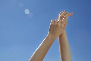 vrouw handen uitrekken na ontwaken omhoog naar de blauw lucht . zonnig dag . jong handen . ochtend- wakker worden omhoog .blauw achtergrond handen omhoog in de lucht .selectief focus foto