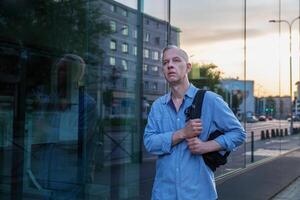 grijs haar Mens in een denim overhemd met een rugzak Aan een stad straat. hoog kwaliteit foto