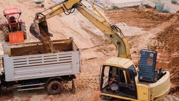 backhoe opgraven grond. bouw plaats, een krachtig backhoe lader manoeuvres bedreven, opgraven de grond in een vrachtwagen, presentatie van de rendement van zwaar machinerie Bij werk. foto