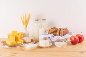 een verschillend kaas, brood, huisje kaas, verzuren room, melk in flessen Aan een houten aanrecht. concept van de Joods vakantie van sjavoeot. voorkant visie foto