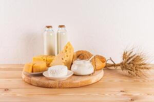 divers zuivel producten. brood, melk flessen Aan een groot ronde houten dienblad Aan een houten tafel. concept van de Joods vakantie van sjavoeot. foto