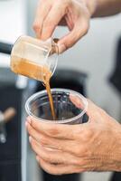 barista gieten koffie van naar plastic kop in koffie winkel foto