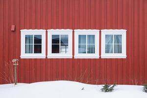 rij wit ramen met houten rood muur en sneeuw foto