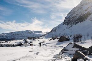 besneeuwd berg en bergbeklimmers wandelen in winter Aan zonnig dag Bij lofoten eilanden foto