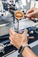 barista gieten koffie van naar plastic kop in koffie winkel foto