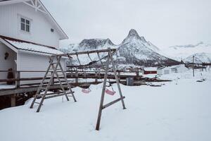 houten schommels blazen Aan speelplaats met besneeuwd berg foto