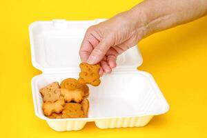 een vrouw hand- zet kinderen koekjes in een lunch doos. foto