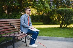 Blind Mens lezing braille boek, zittend Aan bank in zomer park, resting foto