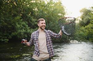 visser vangsten een forel Aan de rivier- in zomer foto