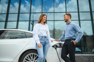 jong paar Mens en vrouw op reis samen door nieuw auto hebben hou op Bij opladen station. foto