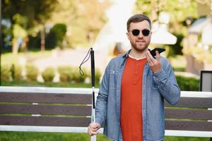 jong verblind Mens gebruik makend van telefoon en Bezig met verzenden stem bericht foto